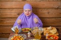 A Muslim woman in a lilac hijab at the table begins a meal, the holiday of Eid al-Fitr says bismi llah. Royalty Free Stock Photo