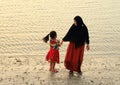 Muslim woman with little girl walking on beach Royalty Free Stock Photo