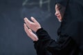 Muslim woman making traditional prayer to God in front of black chalkboard