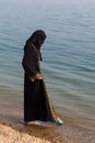 A Muslim woman in national clothes wets her feet Royalty Free Stock Photo