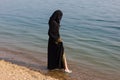 A Muslim woman in national clothes wets her feet Royalty Free Stock Photo