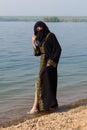 A Muslim woman in national clothes wets her feet Royalty Free Stock Photo