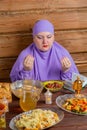 A Muslim woman in a purple hijab at the table for the holiday of Eid al-Fitr says bismi llah raising her hands Royalty Free Stock Photo