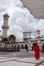 Muslim woman in a red cape standing in a courtyard of the Masjid Jamek Mosque in Kuala Lumpur in Malaysia