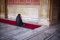 Muslim woman in sari kneeling and praying at the m
