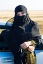 Muslim woman stands near the car with keys hand.