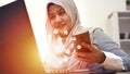 Muslim woman using phone and laptop computer with internet of things graphic icons, mobile wireless technology Royalty Free Stock Photo