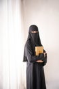 muslim woman wearing a black hijab and long dress holding al qur'an Royalty Free Stock Photo