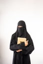 muslim woman wearing a black hijab and long dress holding al qur'an