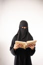 muslim woman wearing a black hijab and long dress reading al qur'an Royalty Free Stock Photo