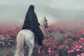 A muslim woman, wearing a black nikab, rides a white horse through a field of pink flowers