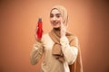 muslim woman wearing hijab t-shirt smiling while applying skincare and holding bottle Royalty Free Stock Photo