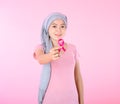 Muslim woman wearing a hijab with a ribbon on her chest shows prevention of breast cancer. On a pink backdrop, breast cancer