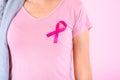 Muslim woman wearing a hijab with a ribbon on her chest shows prevention of breast cancer. On a pink backdrop, breast cancer