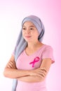 Muslim woman wearing a hijab with a ribbon on her chest shows prevention of breast cancer. On a pink backdrop, breast cancer