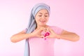 Muslim woman wearing a hijab with a ribbon on her chest shows prevention of breast cancer. On a pink backdrop, breast cancer