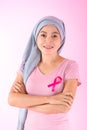 Muslim woman wearing a hijab with a ribbon on her chest shows prevention of breast cancer. On a pink backdrop, breast cancer