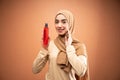 muslim woman wearing hijab t-shirt smiling while applying skincare and holding bottle Royalty Free Stock Photo