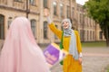 Muslim woman wearing yellow dress waving her friend Royalty Free Stock Photo