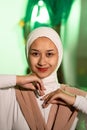 a Muslim woman in a white headscarf and white clothes poses with her hands without the slightest makeup on her face and smiles Royalty Free Stock Photo