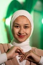 a Muslim woman in a white headscarf and white clothes poses with her hands without the slightest makeup on her face and smiles Royalty Free Stock Photo