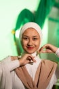 a Muslim woman in a white headscarf and white clothes poses with her hands without the slightest makeup on her face and smiles Royalty Free Stock Photo