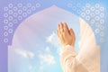 Muslim woman in a white hijab prayerfully folded the hands under a Muslim architectural arch against a blue sky, praying to Allah