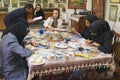 Muslim women artists in black headscarfs paint traditional Persian miniature in a workshop in Isfahan, Iran.
