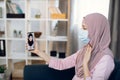 Muslim young woman patient with sore throat, having video chat with Arabian female doctor via smartphone app, sitting on Royalty Free Stock Photo