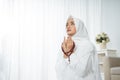 Muslim young woman praying in white traditional clothes