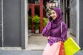 Muslim young woman in veil hijab holding shopping bags walking on the city street. while talking on mobile phone Royalty Free Stock Photo