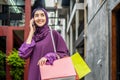 Muslim young woman in veil hijab holding shopping bags walking on the city street. while talking on mobile phone Royalty Free Stock Photo