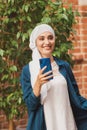 Muslim young woman wearing hijab head scarf in city texting cell phone Royalty Free Stock Photo