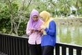 Muslimah enjoying outdoor, having discussion at park and one of them holding mobile phone Royalty Free Stock Photo