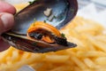 mussel in hand on french fries background at restaura Royalty Free Stock Photo