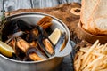 Mussel shells in a gray cauldron in tomato sauce, french fries and croutons on a gray background Royalty Free Stock Photo