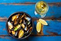 Mussels in clay bowl, glass of white wine and lemon