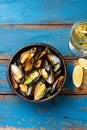 Mussels in clay bowl, glass of white wine and lemon