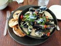 Mussels dish served with a fresh salad, chili pepper and toasted white bread on gray plate in restaurant Royalty Free Stock Photo