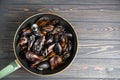 Mussels with parsley and garlic in wog pan on wooden table