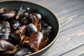 Mussels with parsley and garlic in wog pan on wooden table