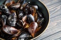 Mussels with parsley and garlic in wog pan on wooden table