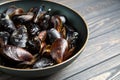 Mussels with parsley and garlic in wog pan on wooden table