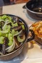 Mussels in a saucepan and fries on a table in a cafe. Traditional Belgian snack. Close-up. Vertical Royalty Free Stock Photo