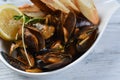 mussels in a shell with sauce, croutons, lemon and sprouts in a white plate