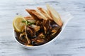 mussels in a shell with sauce, croutons, lemon and sprouts in a white plate