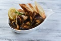 mussels in a shell with sauce, croutons, lemon and sprouts in a white plate