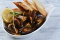 mussels in a shell with sauce, croutons, lemon and sprouts in a white plate