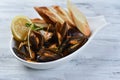 mussels in a shell with sauce, croutons, lemon and sprouts in a white plate