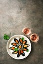 Mussels with spices, parsley and two glasses of pink sparkling wine, dark rustic background. Top view, flat lay, copy space